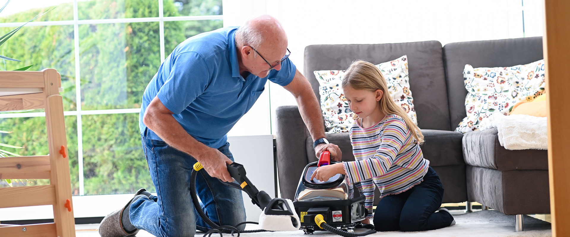 Ein Großvater erklärt seiner Enkelin die einfache Bedienung des Thermostar-Trockendampfreinigers.